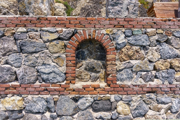 Photo wall and window made of large stones and red brick