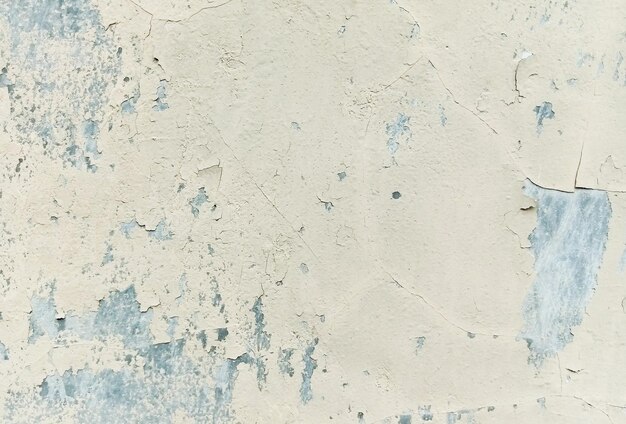 A wall with paint peeling off and a blue paint stain.