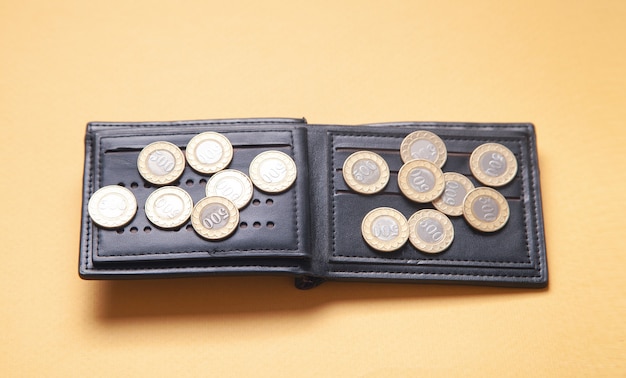 Wallet and coins on the yellow surface.