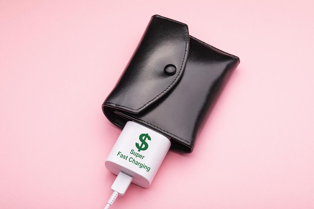 Wallet and smartphone charger on a pink background concept