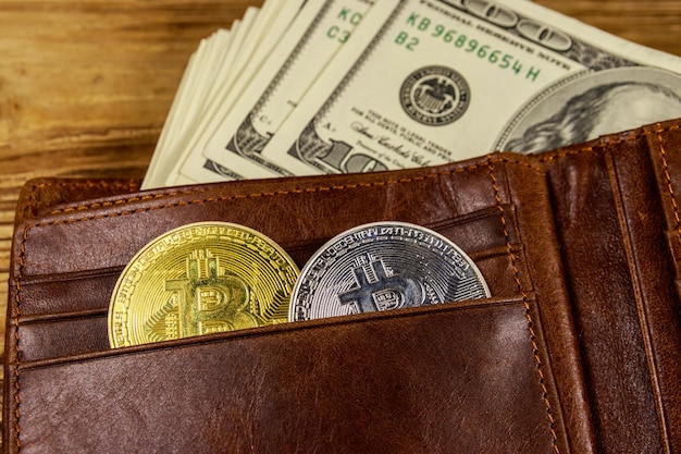 Wallet with american hundred dollars bills and bitcoins on wooden background