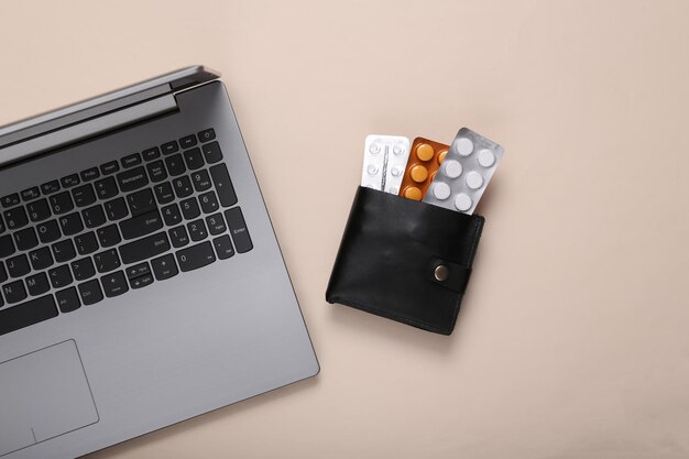 Wallet with blister of pills and laptop on beige background