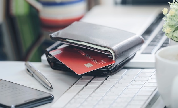 Wallet with credit card on white keyboard.