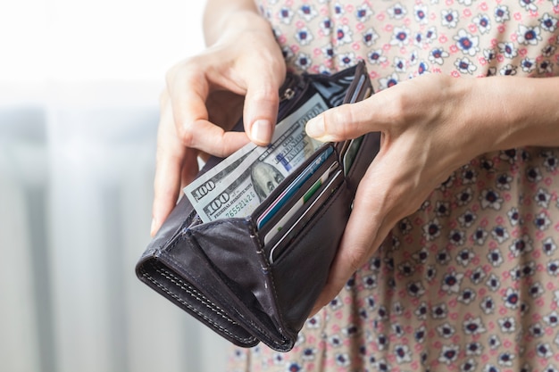 Un portafoglio con dollari nelle mani di una donna. vista dall'alto. il concetto di denaro.