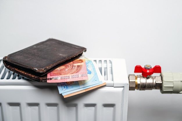 Wallet with euro banknotes on central heating radiator concept of expensive heating costs closeup