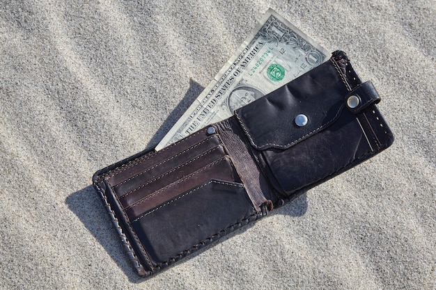 Фото Кошелек с деньгами на песке. концепция снятия наличных