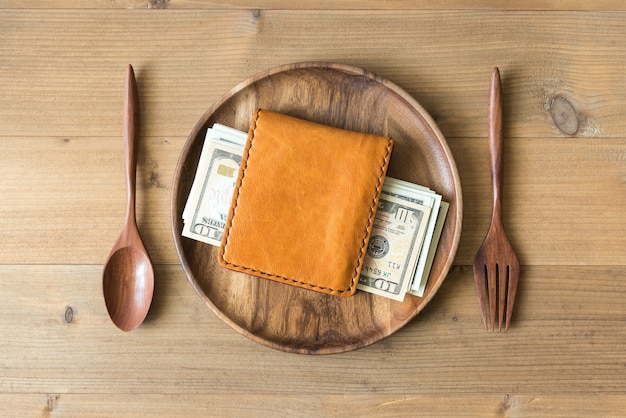 wallet with money in wooden dish