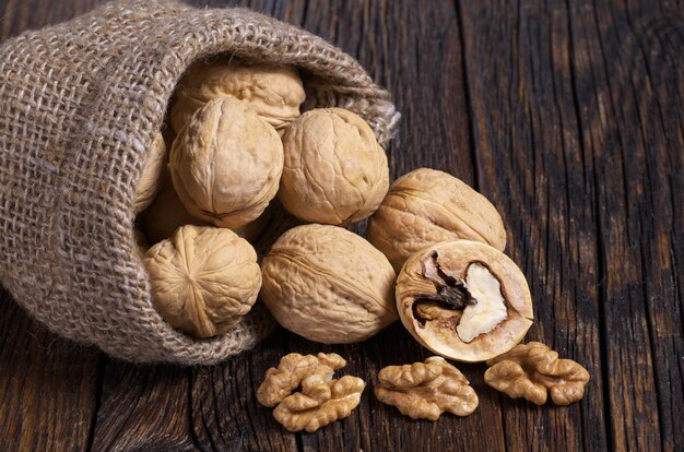 Walnoot in zak en walnoten kernels op rustieke oude houten tafel