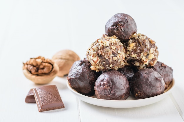 Walnoot, stukjes chocolade en ballen van noten, gedroogd fruit en chocolade op de zwarte tafel. Heerlijk vers huisgemaakt snoep.