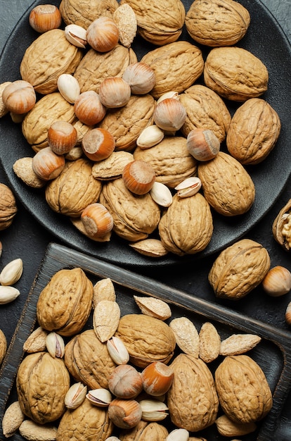 Walnoten in een bord op een donkere betonnen ondergrond. Noten zijn een bron van plantaardige eiwitten en vitamines. Platte bovenaanzicht.