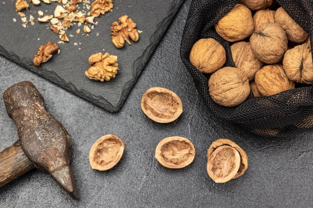 Walnoten in een herbruikbare zak Hamer notendoppen op tafel en notenpitten op stenen bord