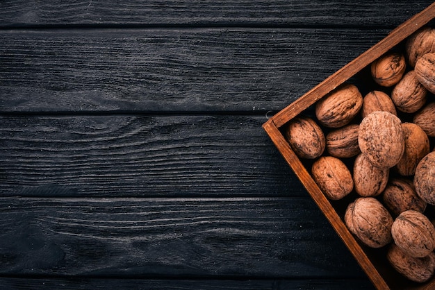 Photo walnut in a box on a wooden background top view copy space