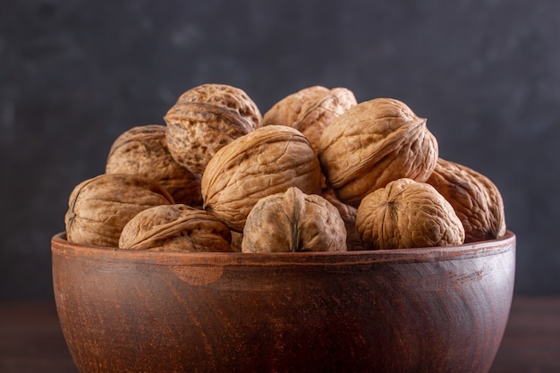 Walnut in a clay bowl close-up against a dark background