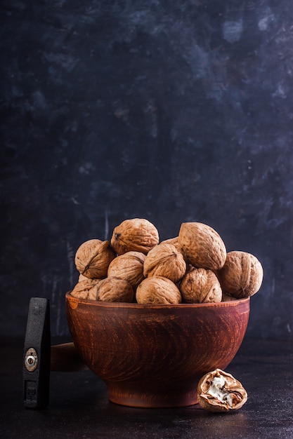 Photo walnut in a clay bowl and a gout on a concrete background. copy space.