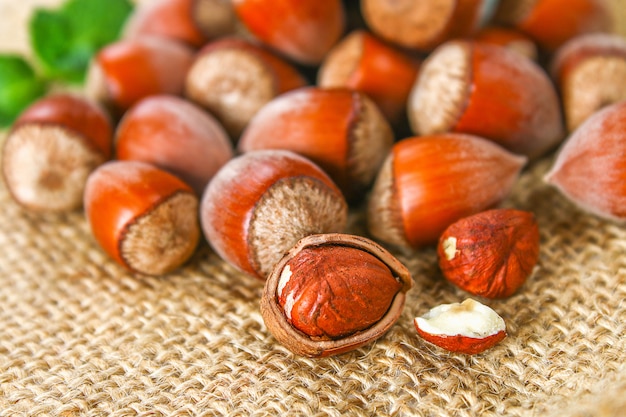 Walnut hazelnuts scattered on sackcloth on a white wooden table.