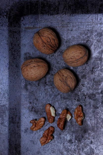 Walnut kernels and whole walnuts on a dark background Vegetarian food concept Closeup View from above