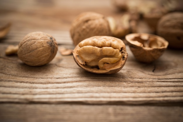 Walnut kernels and whole walnuts on rustic old wooden table