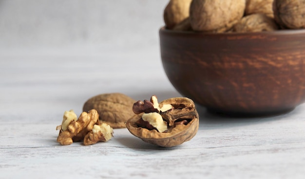 Walnut kernels on a wooden table with a colored background a whole walnut in a wooden vintage bowl