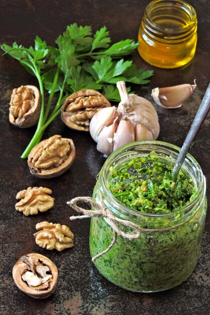 Walnut pesto with parsley. Homemade pesto sauce in a jar. Top view. Vegan pesto with walnut and parsley.