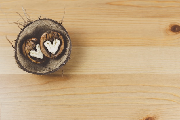 Walnut in the shape of a heart lies in a coconut shell