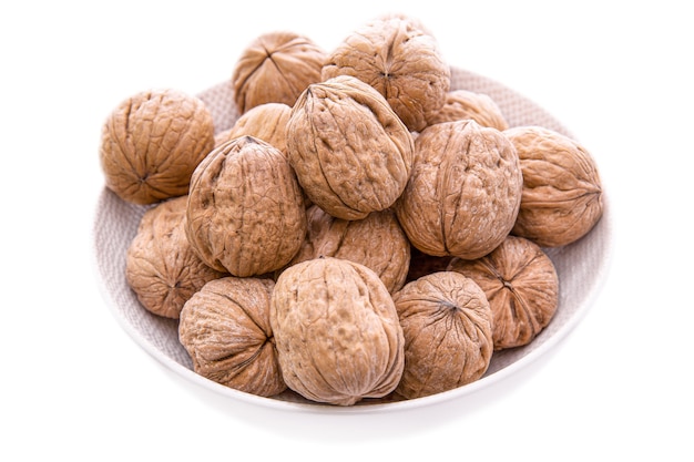 Walnut in a shell in a light plate on a white background.