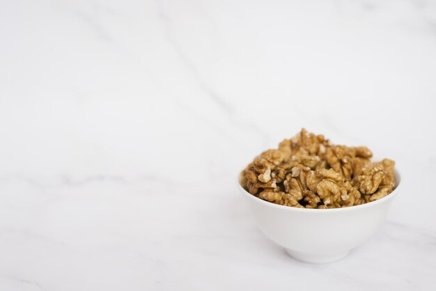 Walnut in a white bowl on a marble table with copy space