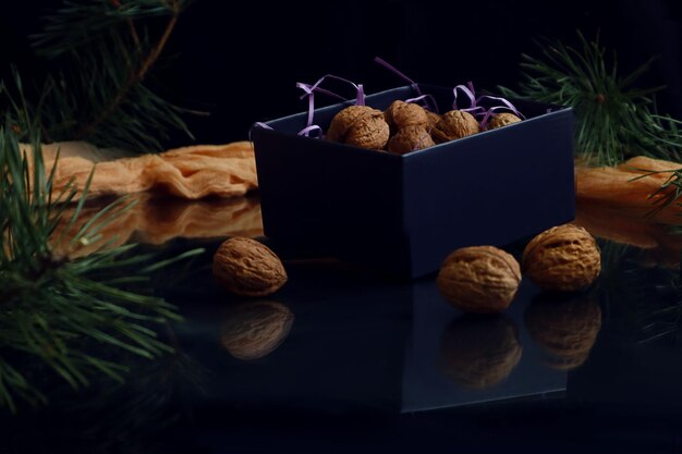 Walnuts in a blue box next to it on a dark background reflection from objects space for text