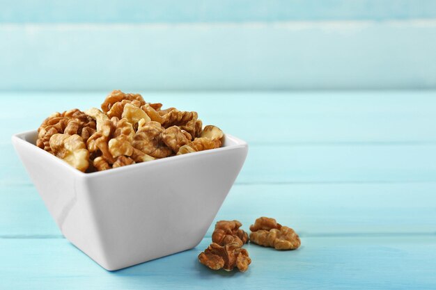 Walnuts in the bowl on blue wooden background