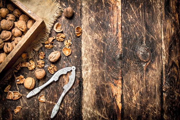 Walnuts in box with Nutcracker on wooden table.