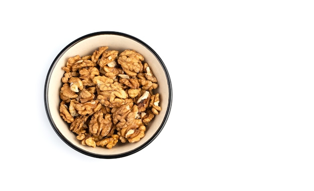 Walnuts in a brown bowl on a white background. Top view with space to copy.