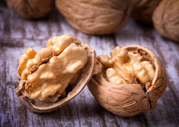 Foto noci su tavolo vintage scuro, gherigli di noci in una ciotola di legno. cibo sano alle noci