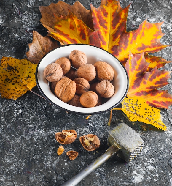 Photo walnuts in an enamel bowl with fallen yellow leaves