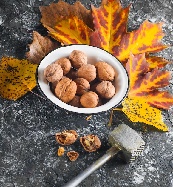 Walnuts in an enamel bowl with fallen yellow leaves