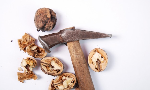 Walnuts and hammer over white background