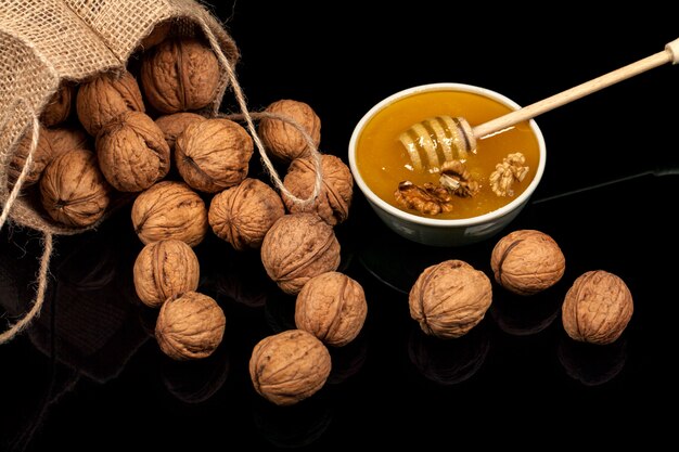 Walnuts and honey in a bag on a black background.