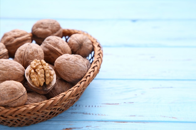 Walnuts kernels in basket on blue wooden background. Walnut healthy food