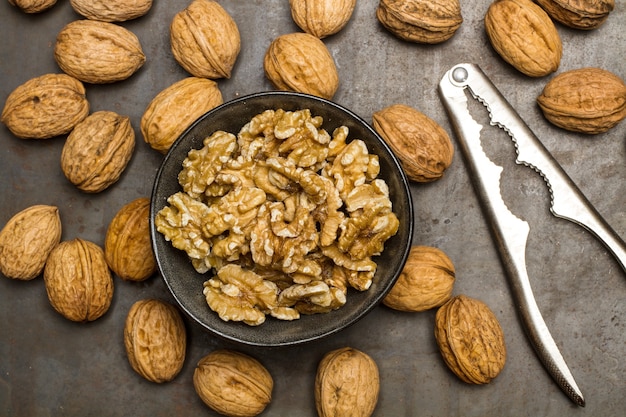 Walnuts kernels in a black bowl and walnuts on a metal table