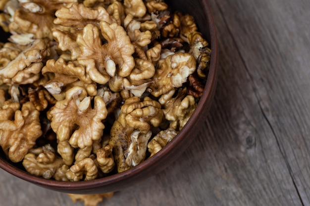 Walnuts kernels in a clay bowl on wooden.