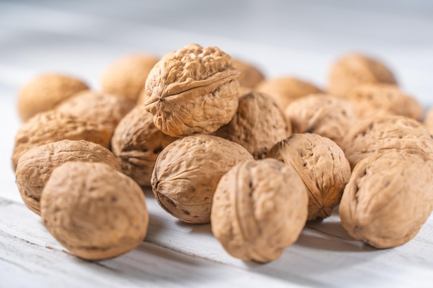 Gherigli di noci sulla scrivania in legno bianco. mucchio di gusci di noci interi