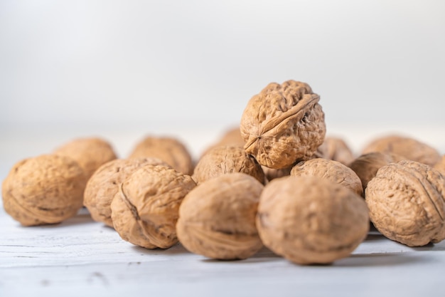 Gherigli di noci sulla scrivania in legno bianco. mucchio di gusci di noci interi