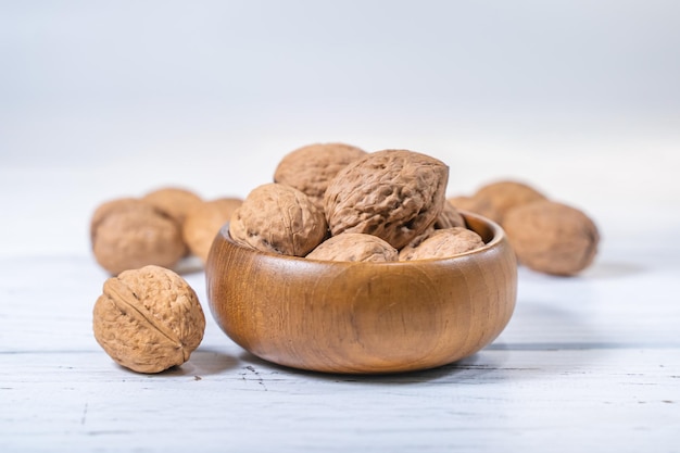 Walnuts kernels on white wooden desk. Whole walnut in wood vintage bowl.