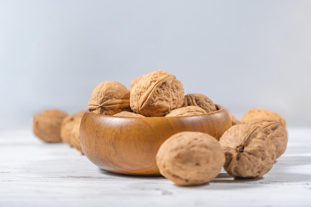 Gherigli di noci sulla scrivania in legno bianco. ciotola vintage in legno di noce intera.