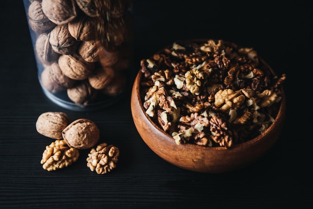 Walnuts kernels in wood bowl on dark desk, Walnut with color background, Whole walnuts in wood vintage bowl. rustic