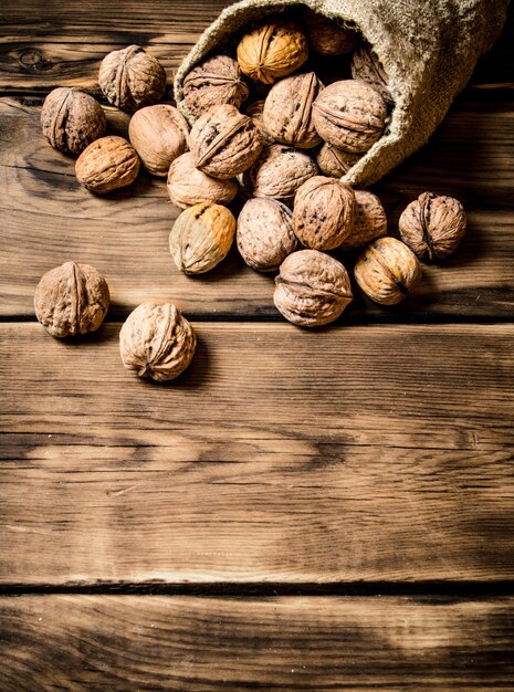 Walnuts in the old bag. On a wooden table.