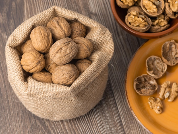 Walnuts out of the sack and in the plate whole shells on the wooden table