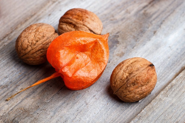 Walnuts and physalis on a wooden background