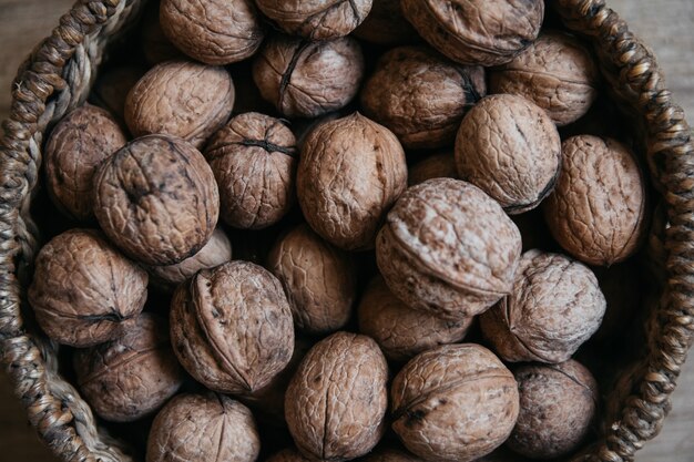 Walnuts in a round wicker basket on a wooden background. Close up.