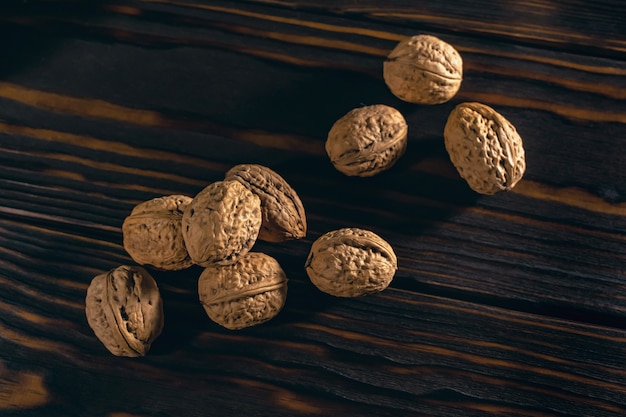 Walnuts in Shell on the Dark Brown Wooden Background. Rustic Backdrop