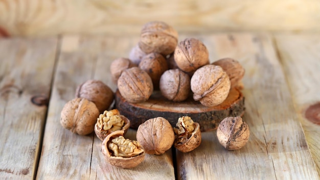 Walnuts in shells on a wooden surface.