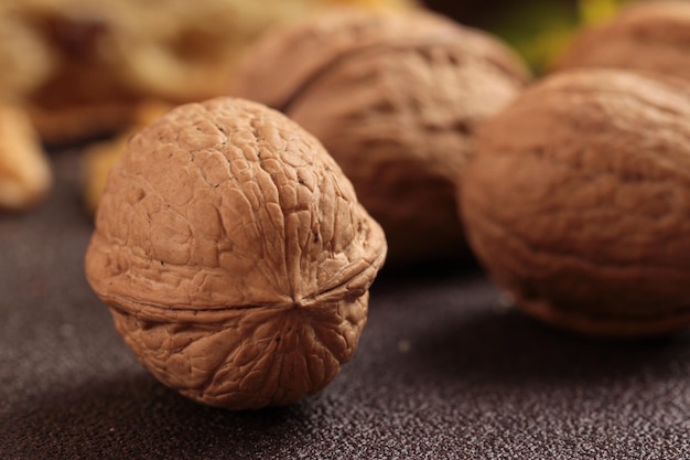 Walnuts on the table one in the foreground and three in the background wooden background closeup view depth of fieldSelective focus